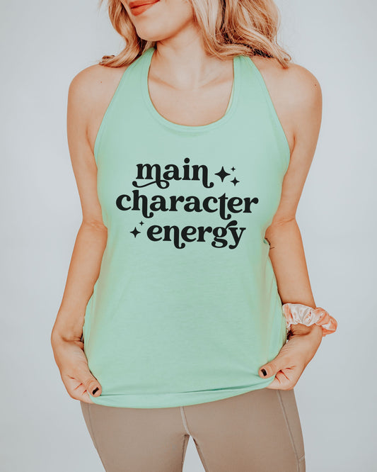 Person wearing a mint green tank top with 'main character energy' text on a plain background
