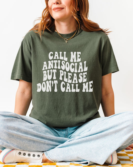 Person wearing a green t-shirt with text sitting on a colorful blanket.