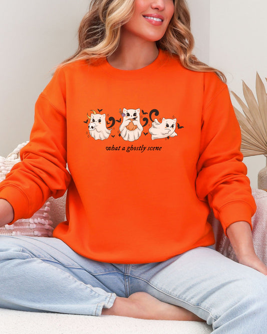 Person wearing an orange sweatshirt with a graphic design of cats and text.