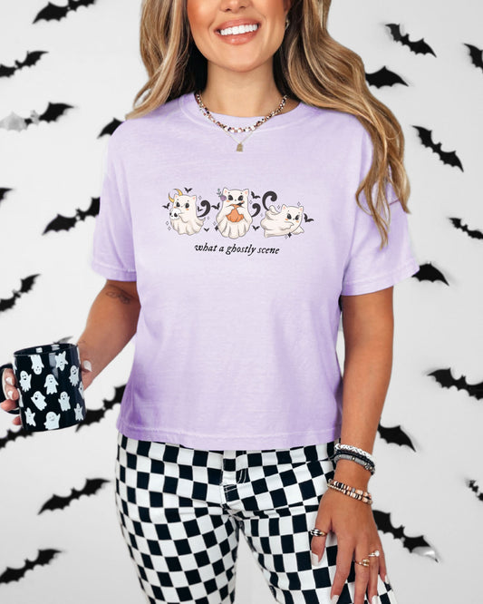 Woman wearing a purple Halloween-themed t-shirt with cartoon ghosts and bats, holding a mug.