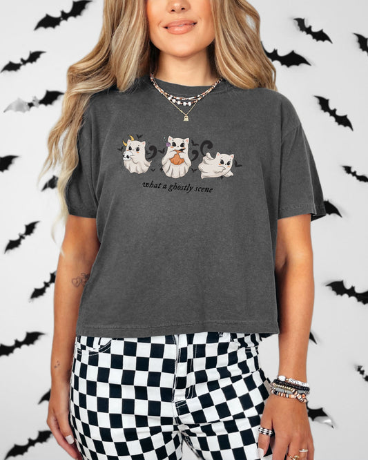 Person wearing a dark gray t-shirt with cat graphics and text, standing against a Halloween-themed background with bats.