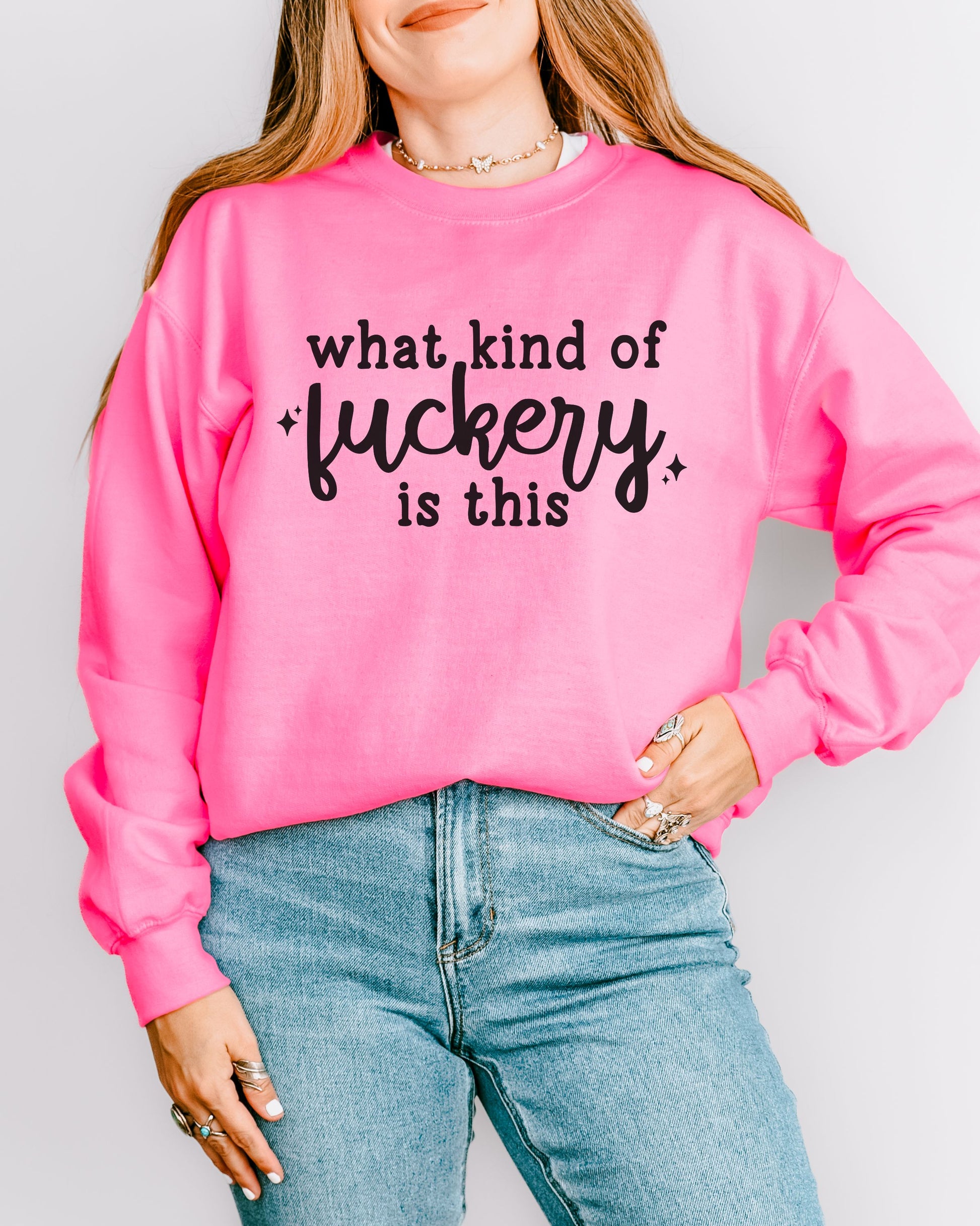 Person wearing a pink sweatshirt with text and blue jeans on a plain background