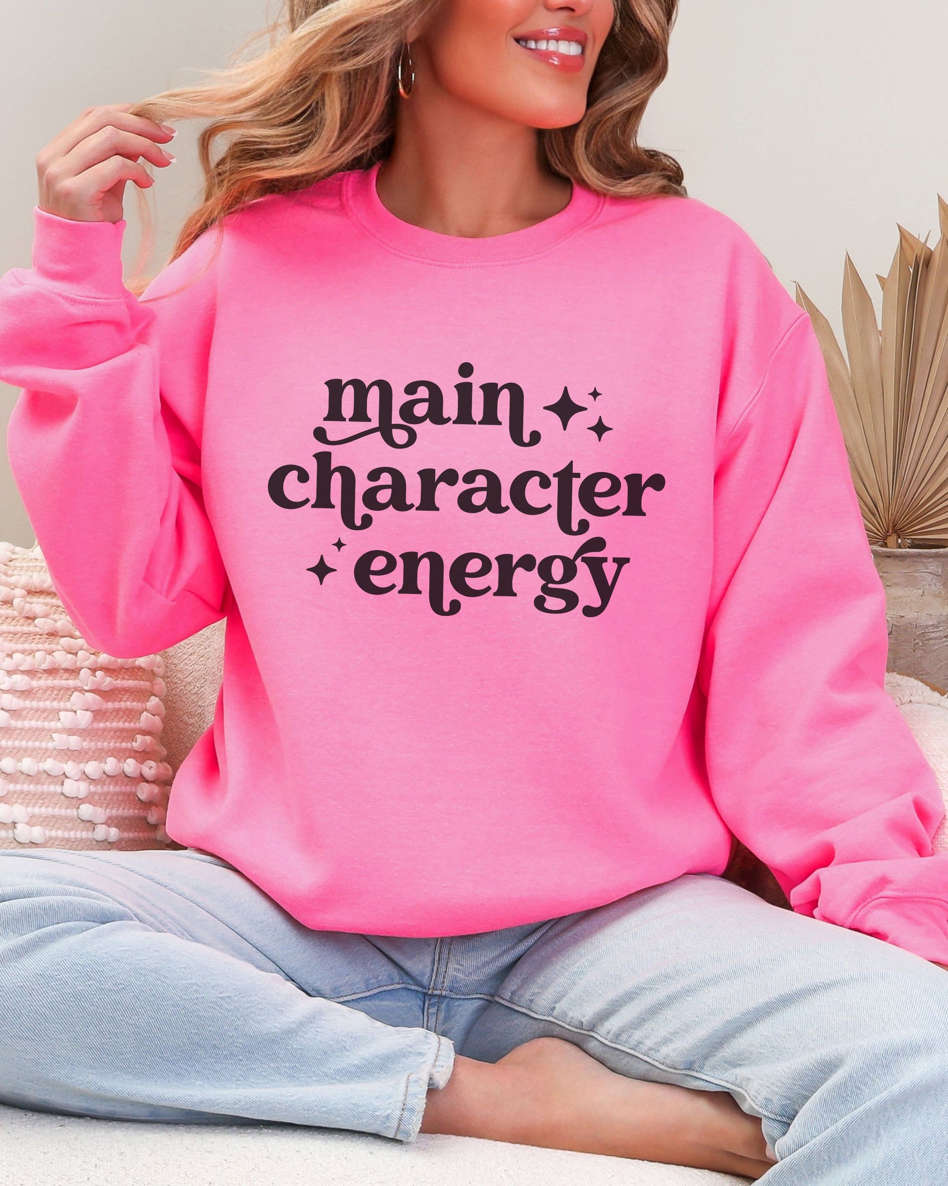 Person wearing a pink sweatshirt with 'main character energy' text.