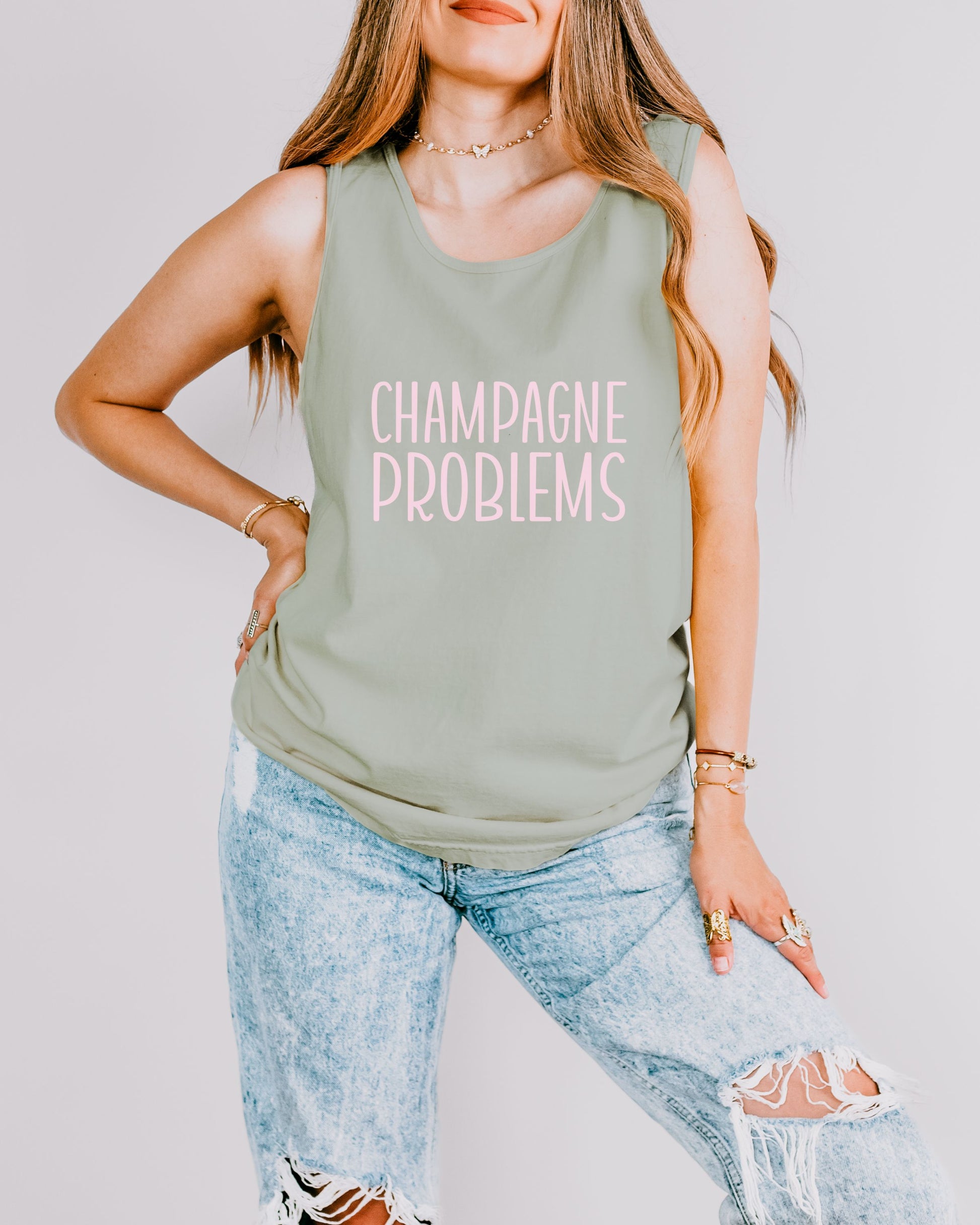 Person wearing a beige tank top with 'Champagne Problems' text on a plain background