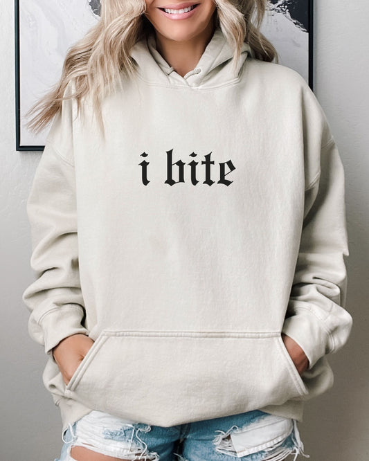 Person wearing a beige hoodie with 'i bite' text, standing against a neutral background.