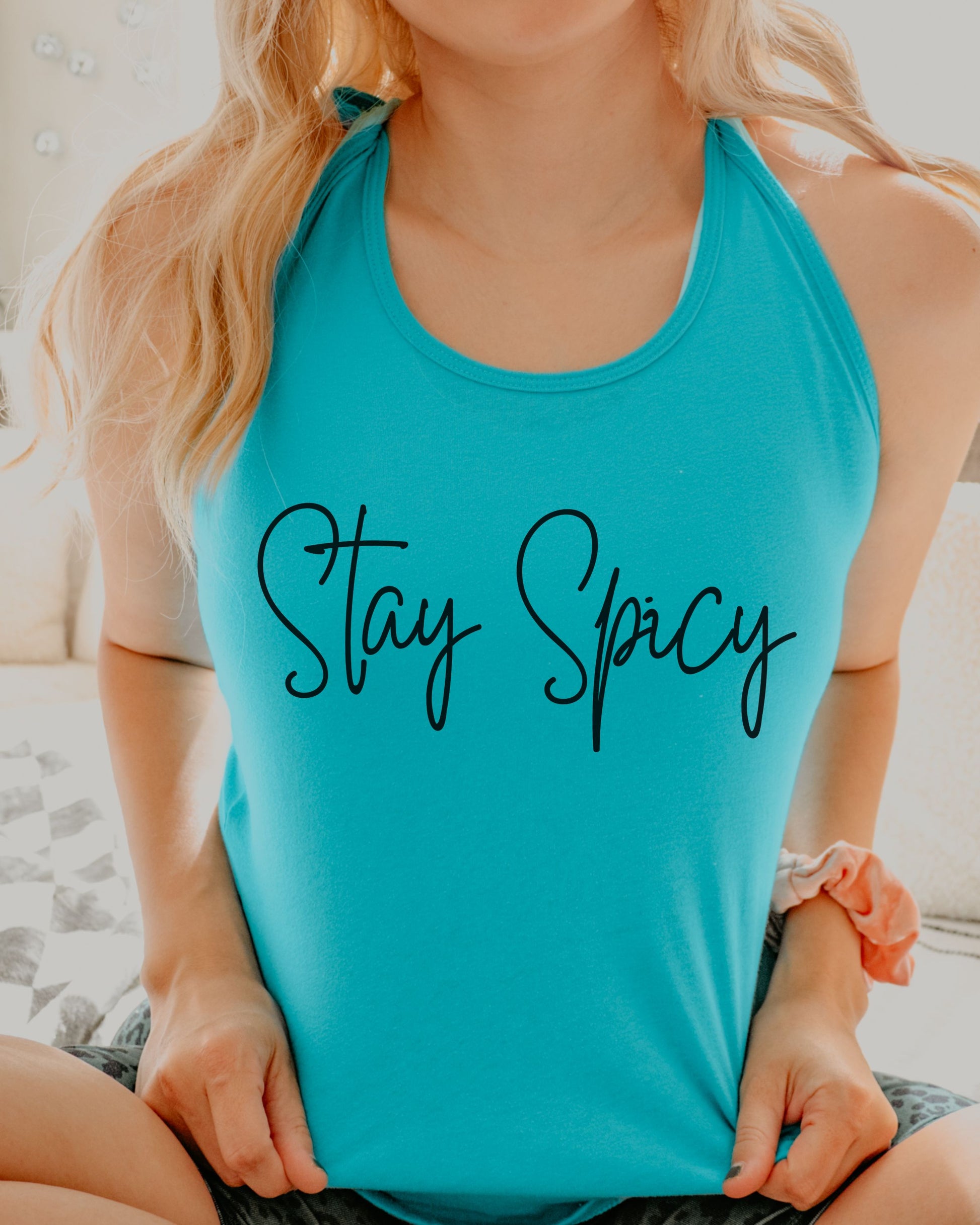 Person wearing a turquoise tank top with 'Stay Spicy' text.