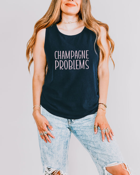 Woman wearing a navy tank top with 'Champagne Problems' text against a plain background