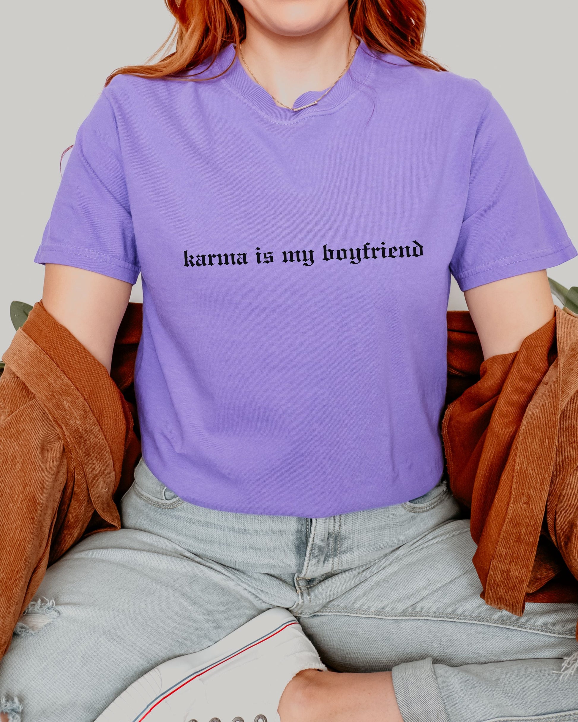 Person wearing a purple t-shirt with 'karma is my boyfriend' text.