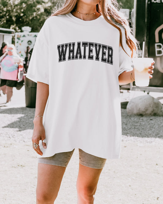 Person wearing a white t-shirt with 'WHATEVER' text, holding a drink.