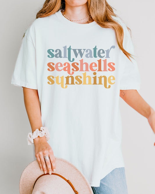 woman wearing beach vibes shirt with saltwater seashells sunshine design

