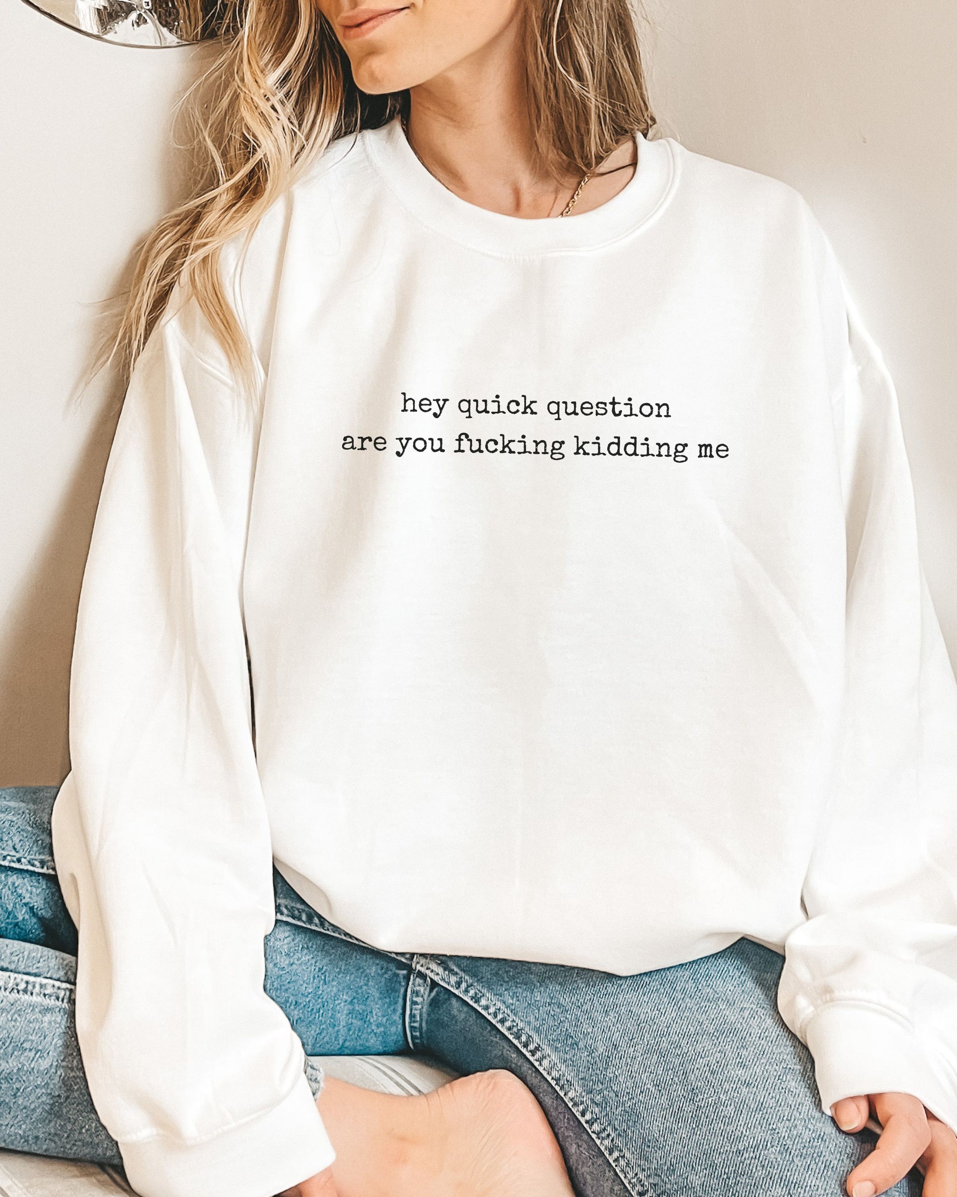 Person wearing a white sweatshirt with text, sitting on a couch.