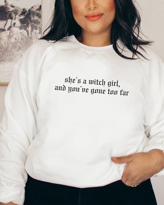 Person wearing a white sweatshirt with text, standing against a neutral background