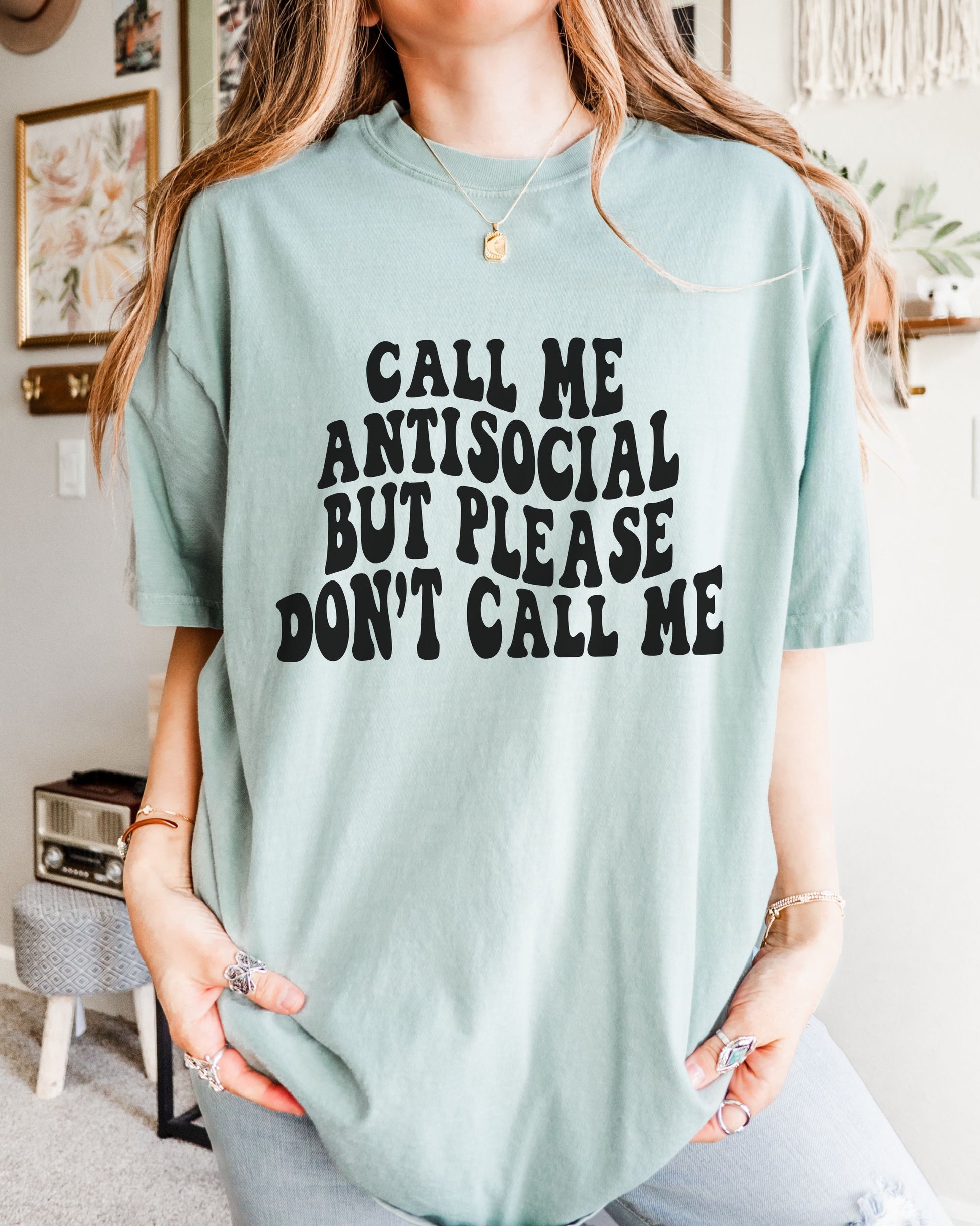 Person wearing a light blue t-shirt with text in a room.
