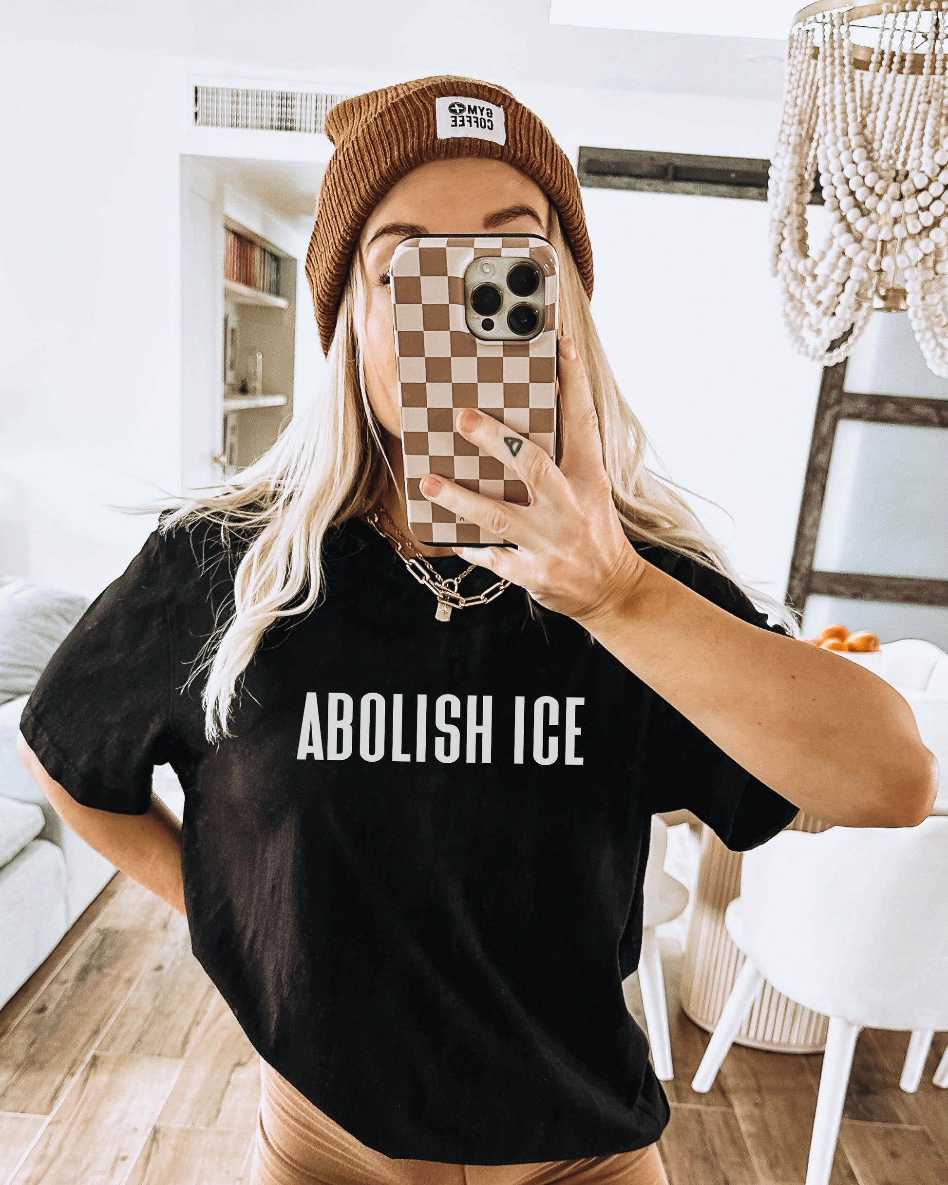 Person wearing a black t-shirt with 'ABOLISH ICE' text, taking a mirror selfie.