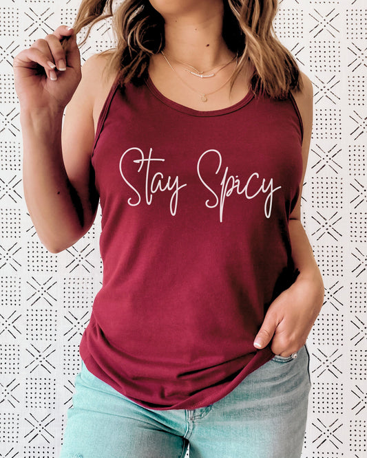 Person wearing a maroon tank top with 'Stay Spicy' text on a patterned background