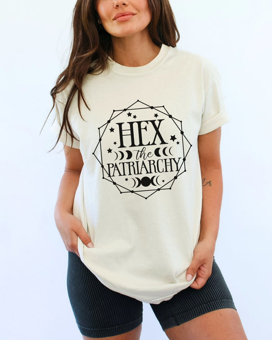 Woman wearing a white t-shirt with 'Hex the Patriarchy' text on a plain background