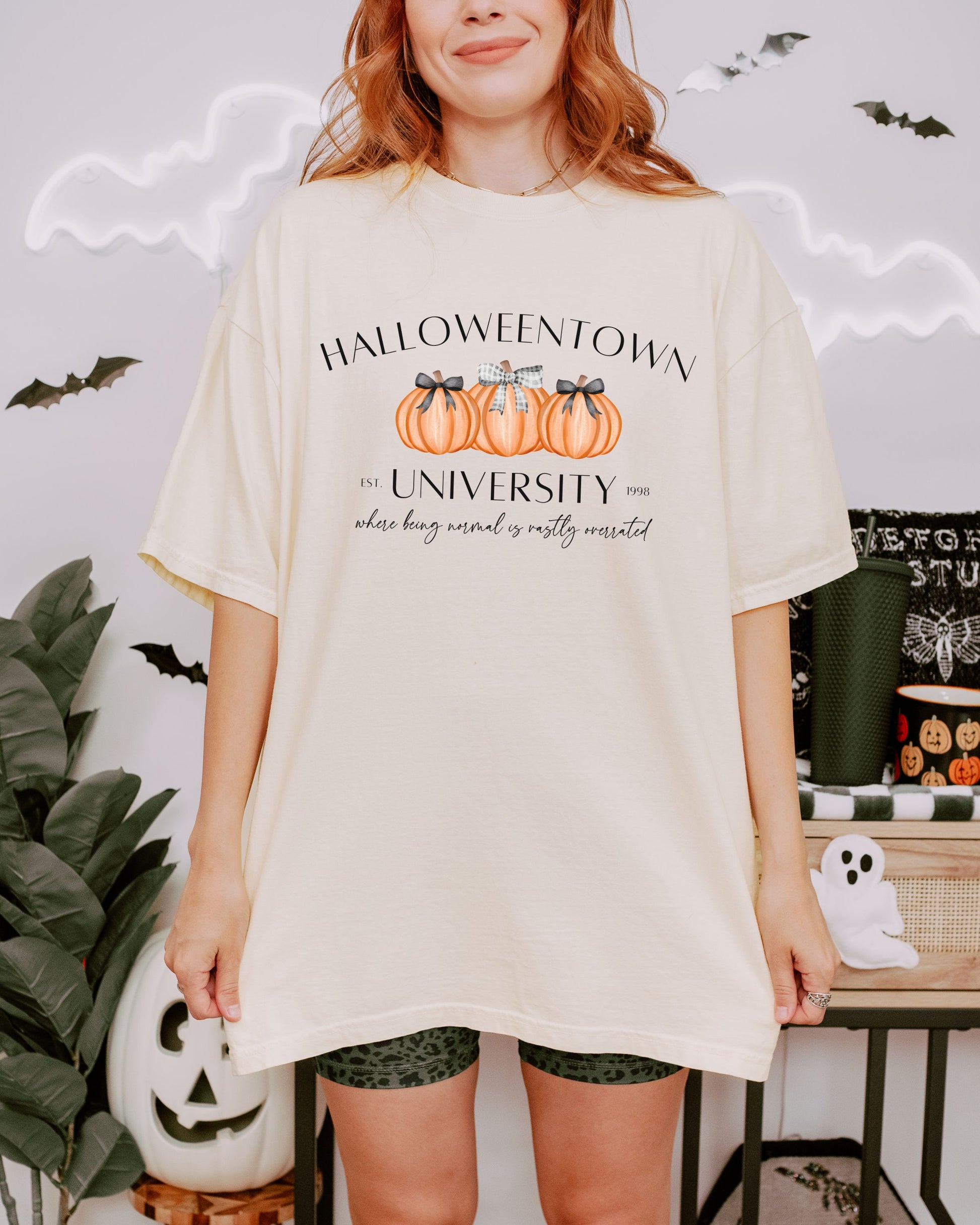 Person wearing a 'Halloweentown University' t-shirt with pumpkins in a Halloween-themed setting.