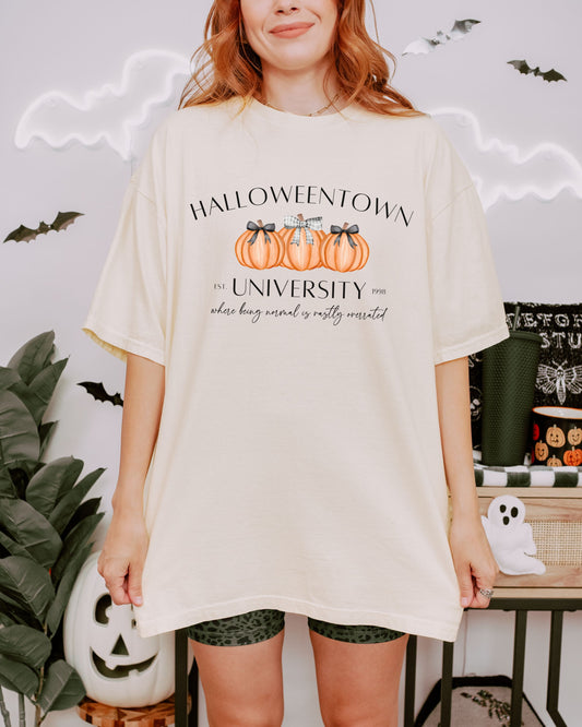 Person wearing a 'Halloweentown University' t-shirt with pumpkins in a Halloween-themed setting.
