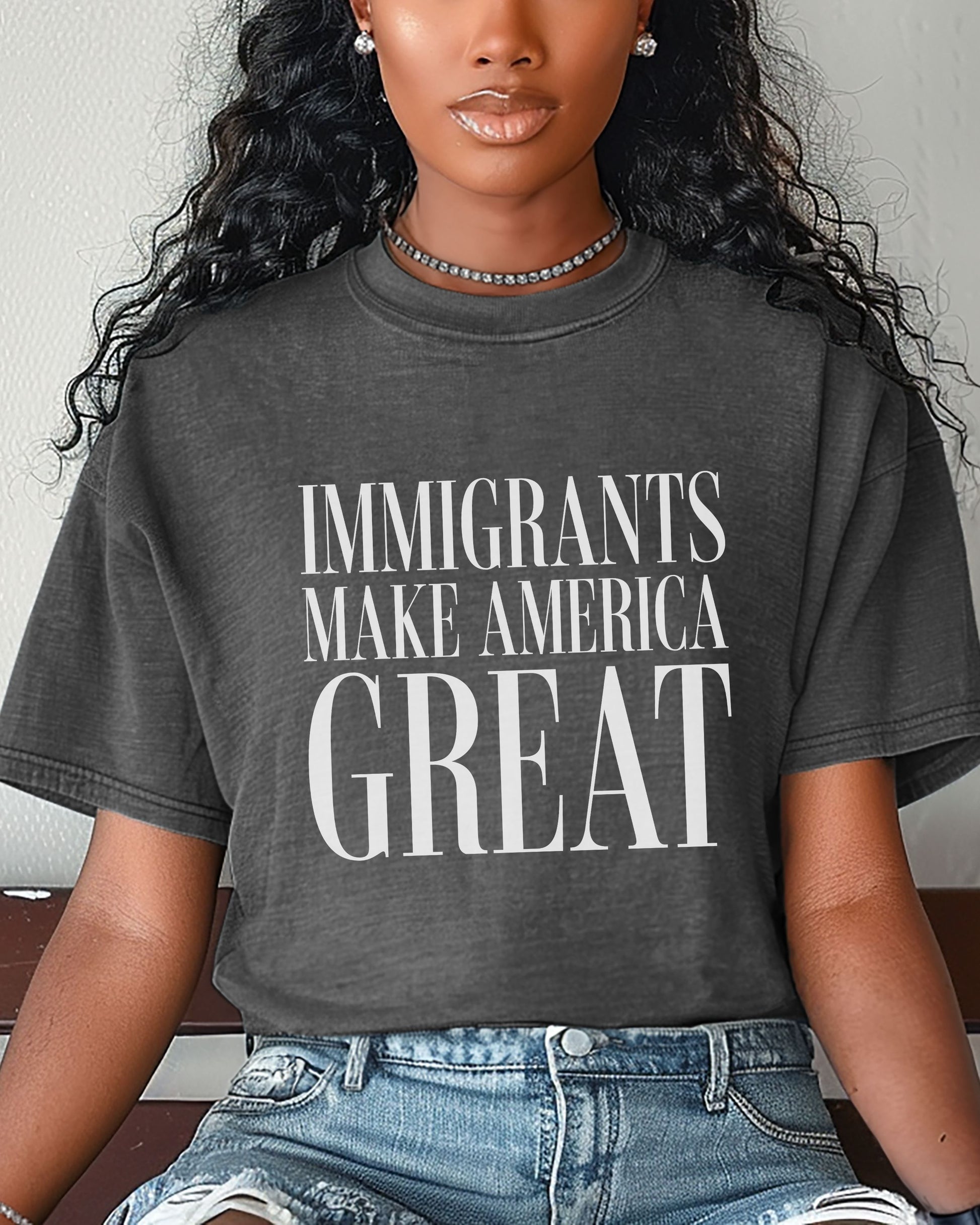 Person wearing a dark gray t-shirt with 'IMMIGRANTS MAKE AMERICA GREAT' text.