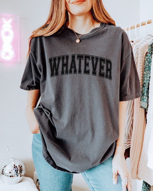 Person wearing a gray t-shirt with 'WHATEVER' text in a casual setting.