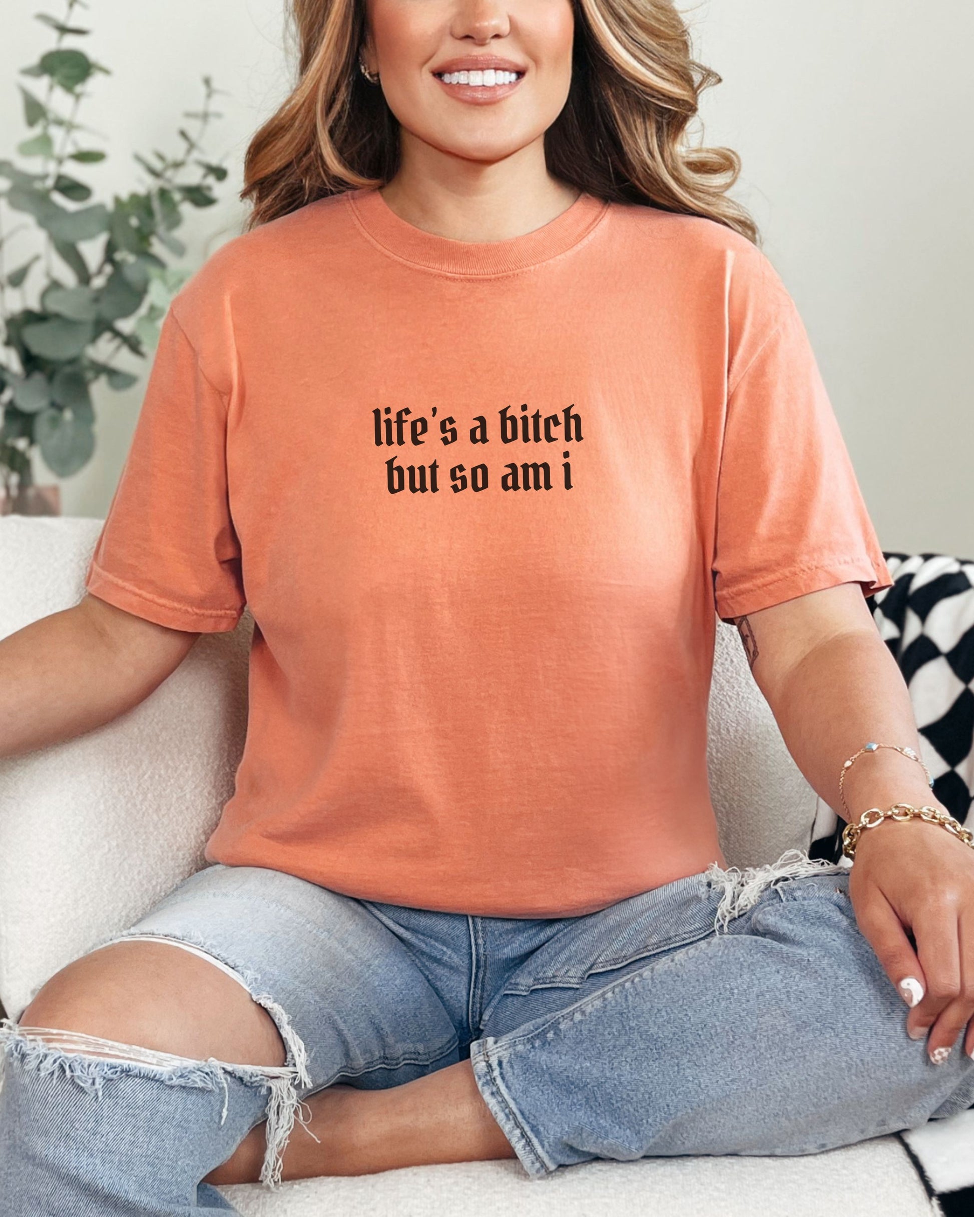 Person wearing an orange t-shirt with text, sitting on a couch.
