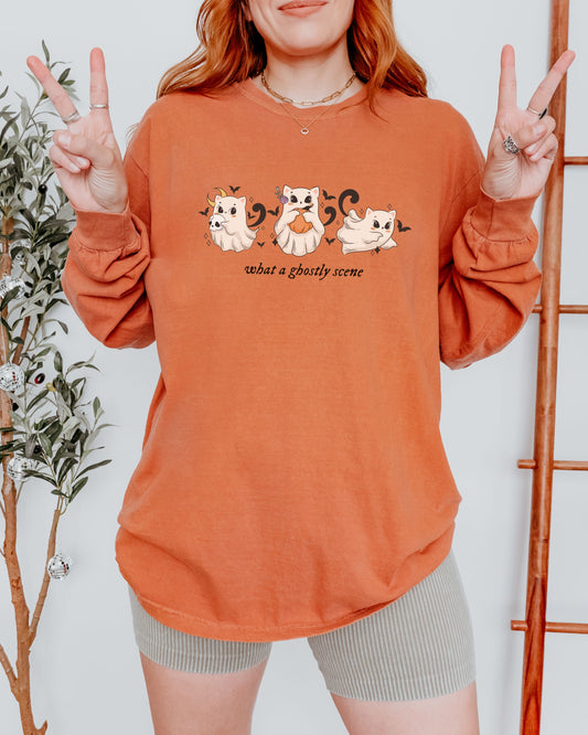 Person wearing an orange sweatshirt with cat graphics and text, making peace signs.